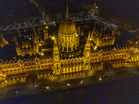 Budapest, Hungary - 15 March 2024: Aerial view of the Hungarian Parliament Building illuminated at night with its grand Neo-Gothic facade, central dome, and spires.
