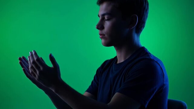 Young man gesturing on green screen background.