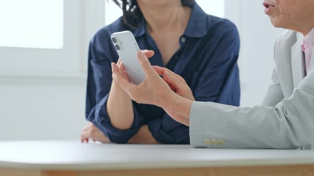 スマホを見る女性とシニア男性