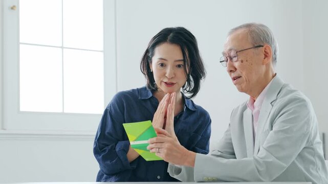 通帳を見て喜ぶ女性とシニア男性