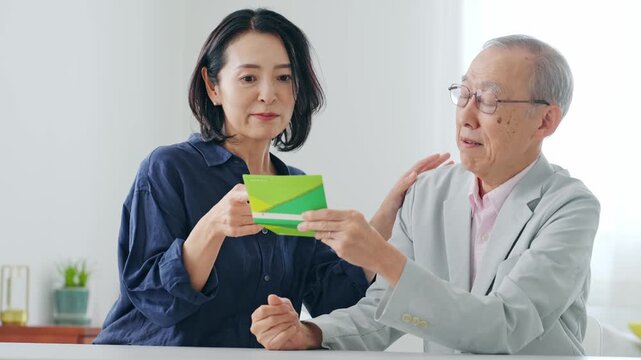 通帳を見てお金をねだる女性とシニア男性