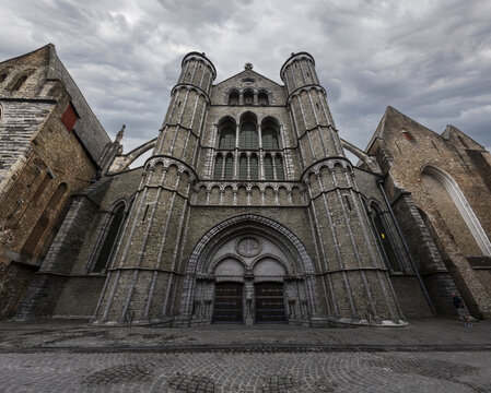 The imposing entrance of Onze-Lieve-Vrouwekerk on Mariastraat in Bruges, Belgium, showcasing Gothic architecture against a moody sky.