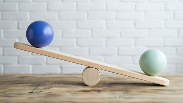 Balance concept with seesaw and colored spheres showing stability and equilibrium on wooden surface