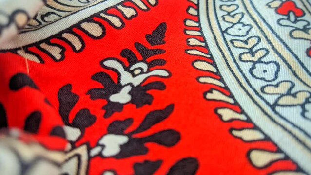 Traditional paisley batik fabric pattern with intricate floral details and red accents close up video
