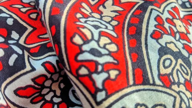 Traditional paisley batik fabric pattern with intricate floral details and red accents close up video
