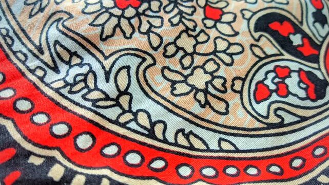 Traditional paisley batik fabric pattern with intricate floral details and red accents close up video
