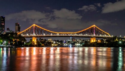 Fototapeta premium Illuminated Steel Bridge Spanning Calm River at Night in Urban Cityscape