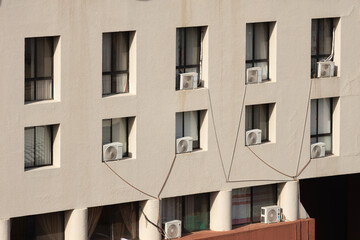 Fototapeta premium The wall of a building with wide windows. The beige-colored wall of a building with brick-colored balconies, and with some windows featuring air conditioners.