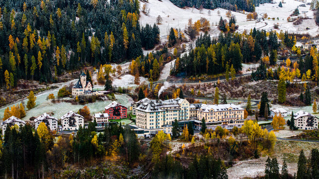 Scuol, Switzerland - 28 October 2025: Aerial view of Hotel Scuol Palace nestled among autumn trees and a light dusting of snow in the alpine landscape of Graubunden.