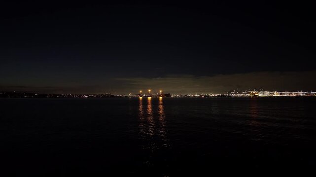 Gimbal wide static shot of the Port of Los Angeles from the Cabrillo Beach jetty at night in San Pedro, California. 4K
