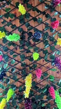 Colorful grape clusters and vine leaves decorate a wooden lattice wall, Georgia