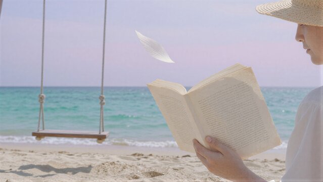 Beachside reader in straw hat, book open, swing and waves behind.