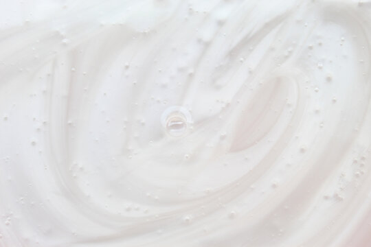 White cosmetic cream or liquid lotion background texture with swirls and air bubbles