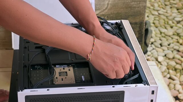 Close up of hands arranging cables inside a white computer case during a PC build