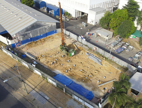 Drone Side View of Pile Driving Machine Operating at Construction Site During Foundation Work.
