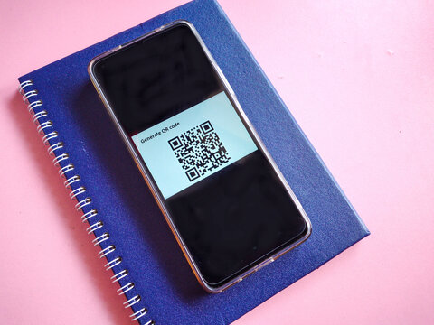Smartphone Showing QR Code Generator App and notebook