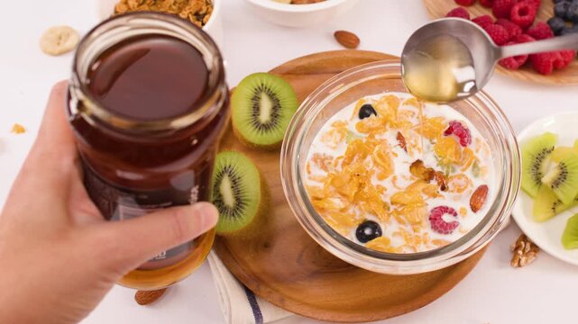 Pouring Golden Honey Over Healthy Cereal Bowl With Fresh Fruit