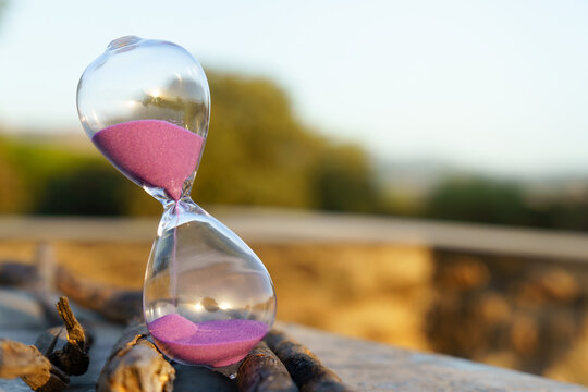 Glass hourglass with vivid purple sand gracefully flowing, measuring duration and symbolizing the passing of time and a deadline