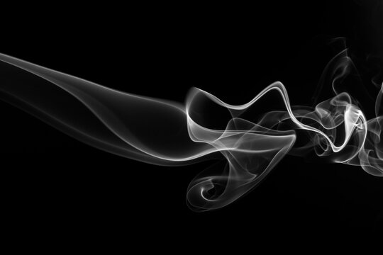 White smoke swirling and moving horizontally on a solid black background.