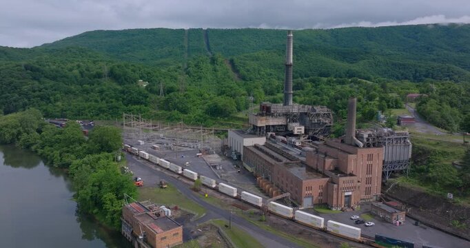 Glen Lyn coal station with freight train and forested mountain backdrop, drone pullback overview