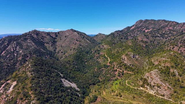 Sierra de Espada national park in Spain, sweeping mountain landscape with forested ridges, winding dirt paths, rocky terrain and clear blue sky