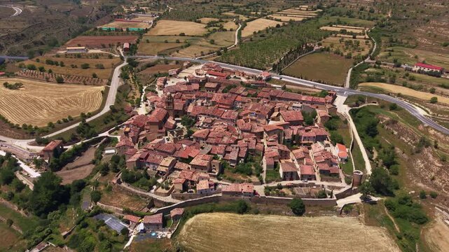 Overhead view of Mirambel medieval walled village revealing intact 13th century stone perimeter walls enclosing dense terracotta rooftops and narrow streets, Maestrazgo, Aragon, Spain