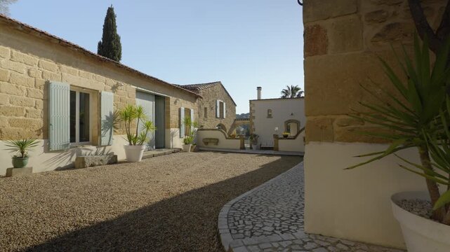 Restored mas courtyard, gravel garden, yucca plants, clear blue sky, France.