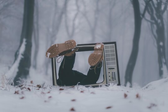 Person looking out of an old tv set in snowy forest