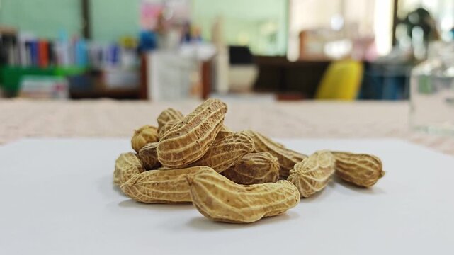 Heap of boiled peanuts in shells on white surface with blurred background.
