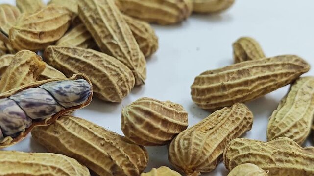 Closed up of boiled tiger stripe peanut showing grains in cracked shell on white background.
