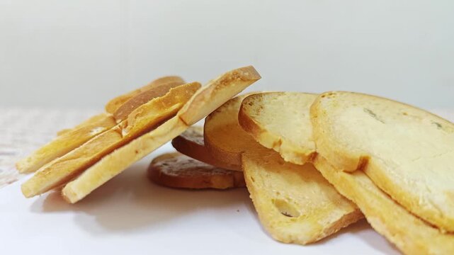 Heap of crispy baked bread rusks leaning on white background.