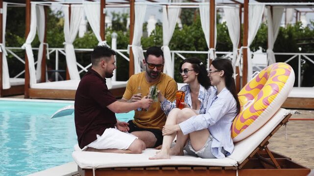 Happy friends having a poolside party with drinks and relaxed atmosphere. Concept celebration, vacation and lifestyle.

