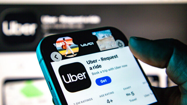Closeup of a hand holding a smartphone displaying the uber app page on the apple app store