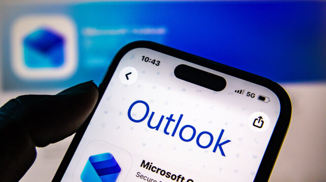 Closeup of a hand holding a smartphone displaying the microsoft outlook app store page on a screen