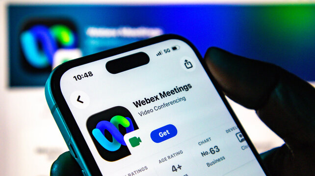 Closeup of a hand holding a smartphone displaying the webex meetings app store page on a screen