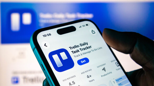 Closeup of a hand holding a smartphone displaying the trello app store page for downloading task management software