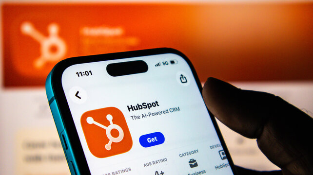 Closeup of a hand holding a smartphone displaying the hubspot app store page on a screen