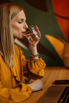 Woman hydrating during remote work, prioritizing wellness and productivity