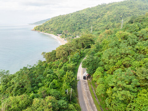 Puerto Princesa City, Philippines - 17 November 2025: Aerial view of a winding coastal road surrounded by dense tropical forest and lush greenery along the turquoise sea.