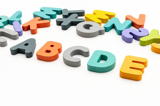 High Angle Studio Shot of Colorful Wooden Alphabet Letters Arranged on White Background
