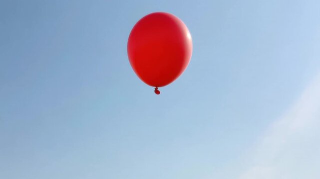 Red balloon drifting away into blue sky with outstretched hand reaching up toward it in clear sunny outdoor setting with minimalistic background