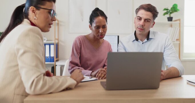 Couple advisor meeting for finance consultation. Advisor outlines loan terms and mortgage options. Couple reviews documents on laptop and plans savings. Clear concept of financial guidance.
