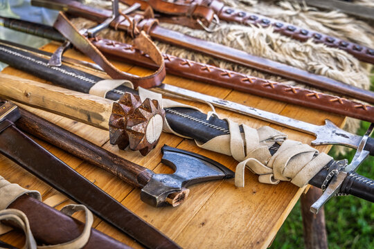 Collection of historical medieval weapons and armor laid out on a wooden table