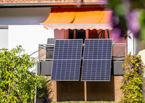 Balcony solar panels installed on a residential building under a clear blue sky