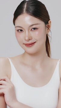 Vertical footage beautiful young Asian woman with healthy facial skin isolated over white background for skincare commercial product advertising. Slow motion shot.