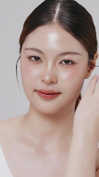 Vertical footage beautiful young Asian woman with healthy facial skin isolated over white background for skincare commercial product advertising. Slow motion shot.