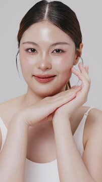 Vertical footage beautiful young Asian woman with healthy facial skin isolated over white background for skincare commercial product advertising. Slow motion shot.