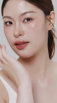 Vertical footage beautiful young Asian woman with healthy facial skin isolated over white background for skincare commercial product advertising. Slow motion shot.