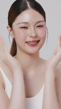 Vertical footage beautiful young Asian woman with healthy facial skin isolated over white background for skincare commercial product advertising. Slow motion shot.