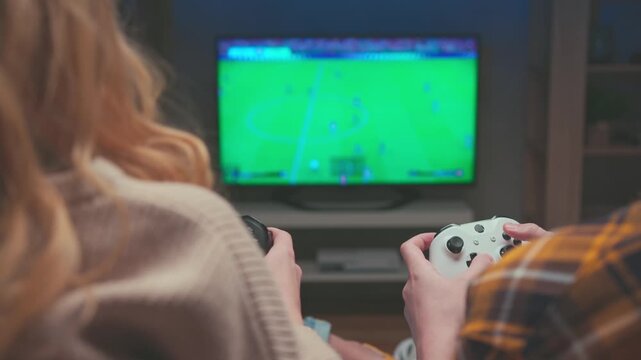 Closeup of Female and Male Hands Holding Controllers during Soccer Videogame. Unrecognizable Couple Uses Black and White Gamepads to Play Football Match. Home Digital Leisure Technology 4k